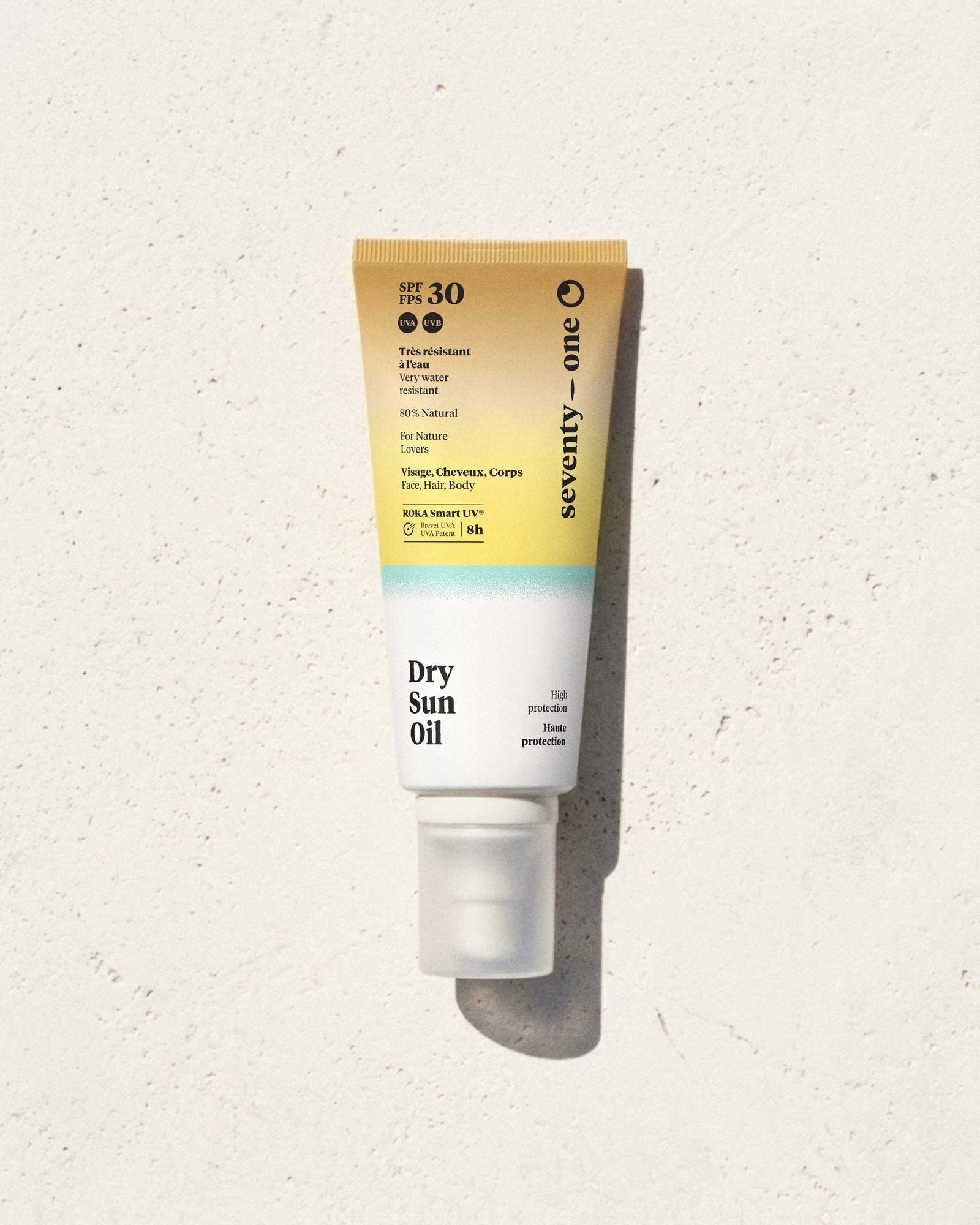 Dry Sun Oil SPF 30 SeventyOne Percent, huile solaire sèche visage, corps et cheveux 100 ml, tube posé sur une pierre blanche au soleil