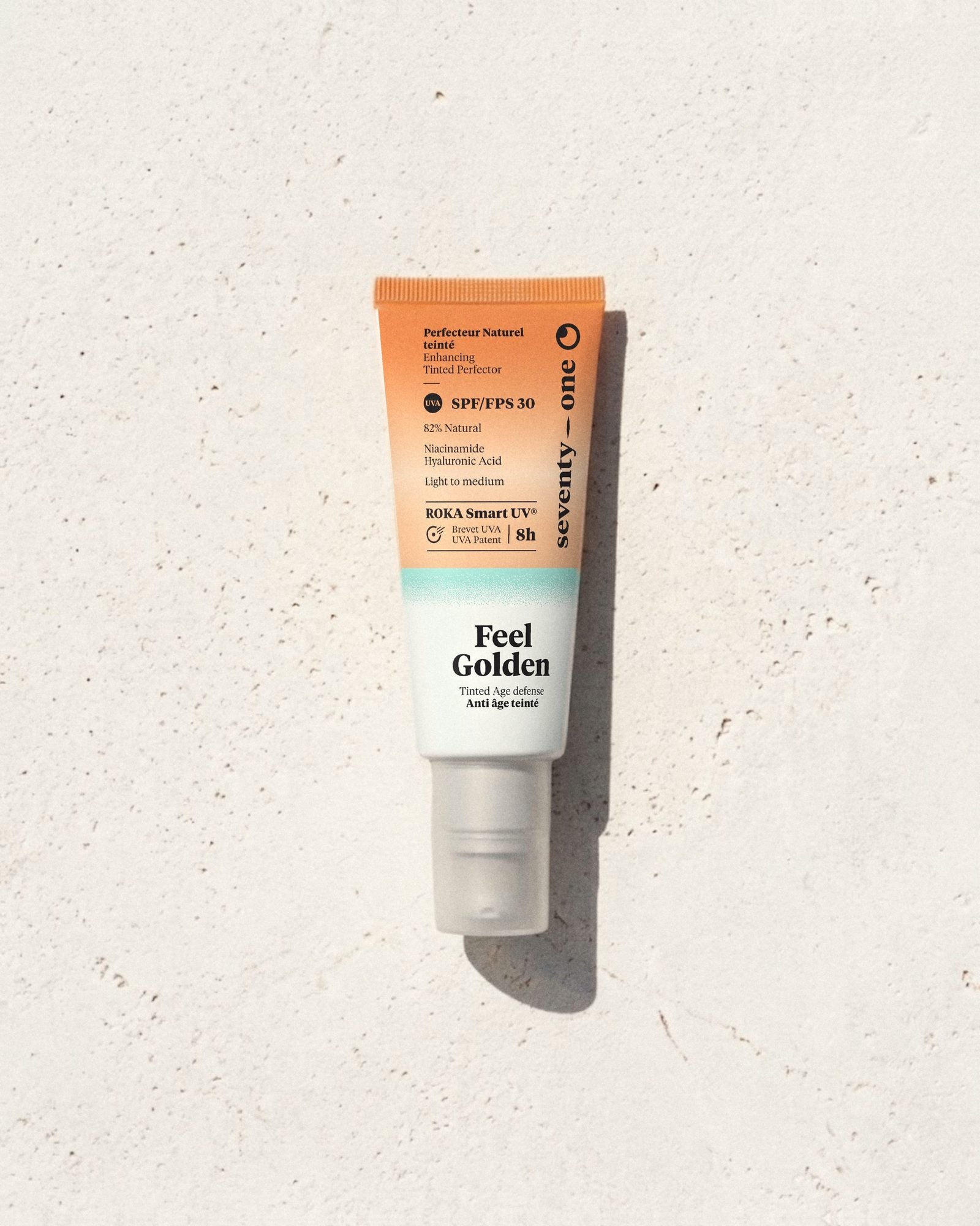Feel Golden SPF 30 SeventyOne Percent, perfecteur de teint teinté anti-âge à la niacinamide 40 ml, tube posé sur une pierre blanche au soleil