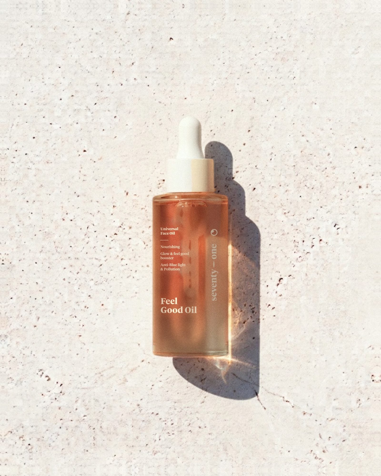 Feel Good Oil SeventyOne Percent, huile visage universelle nourrissante 30 ml, flacon compte-gouttes posé sur une pierre blanche au soleil