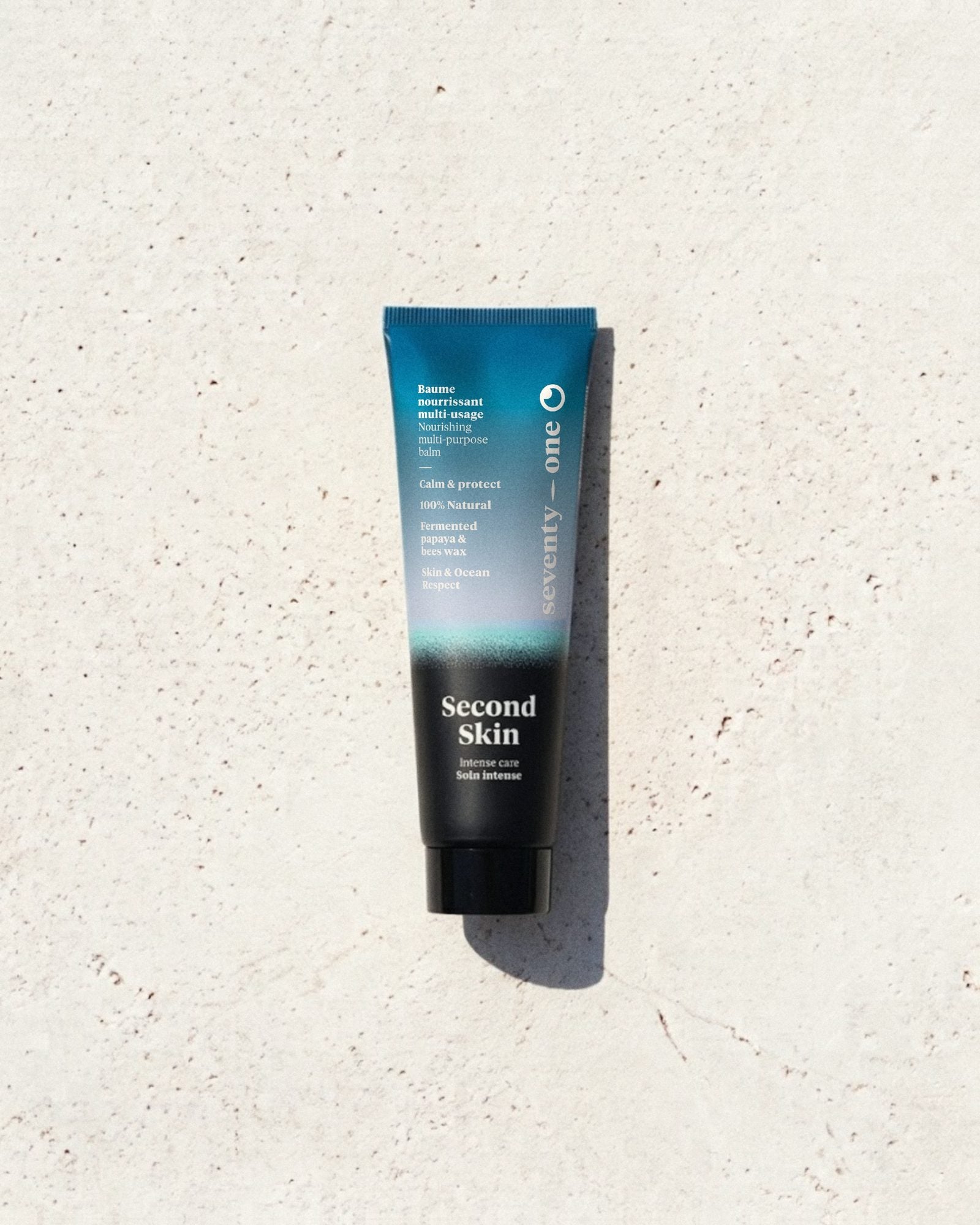 Second Skin SeventyOne Percent, baume nourrissant multi-usage à la papaye fermentée 30 ml, tube posé sur une pierre blanche au soleil