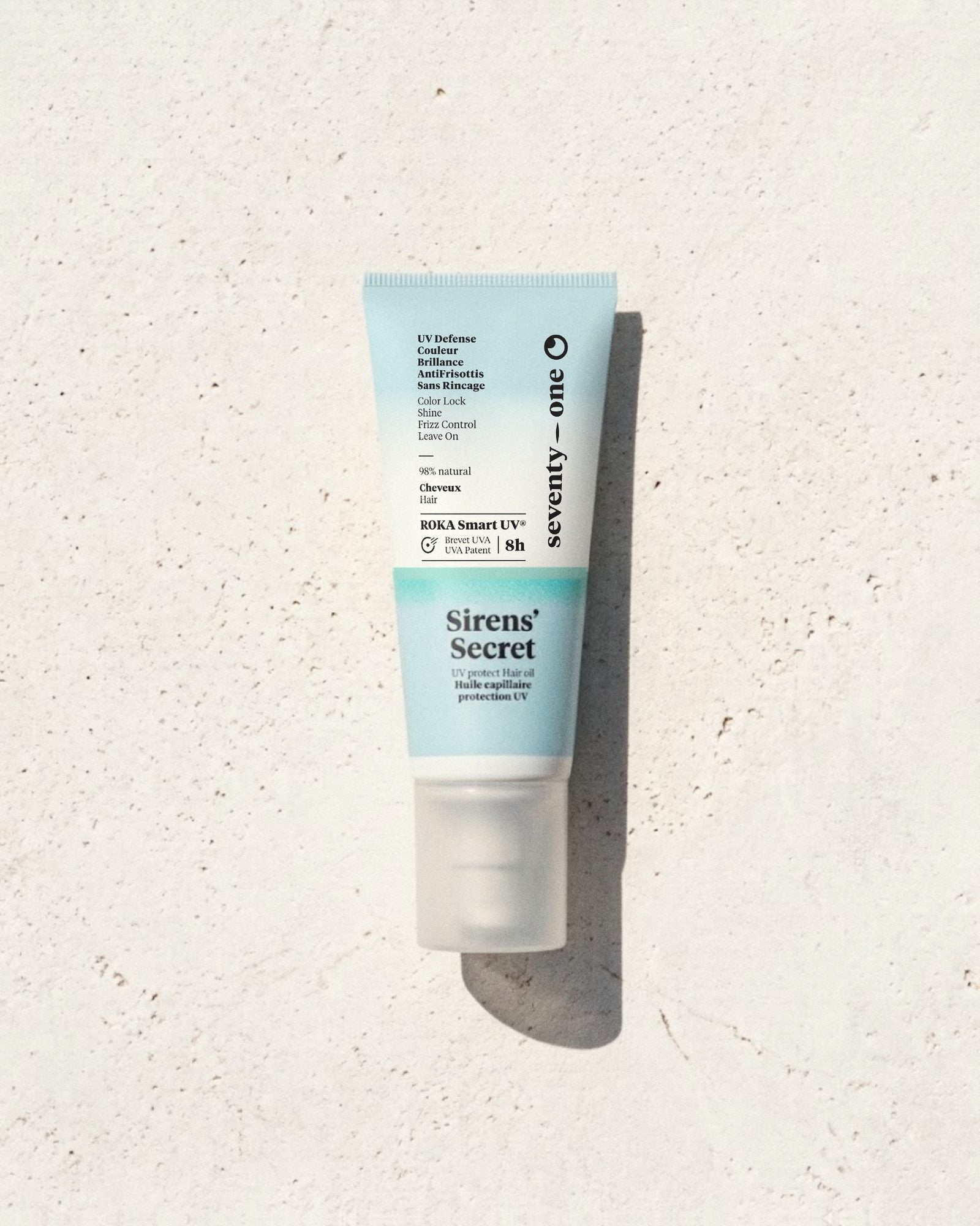 Siren's Secret SeventyOne Percent, huile capillaire protection UV sans rinçage 50 ml, tube posé sur une pierre blanche au soleil