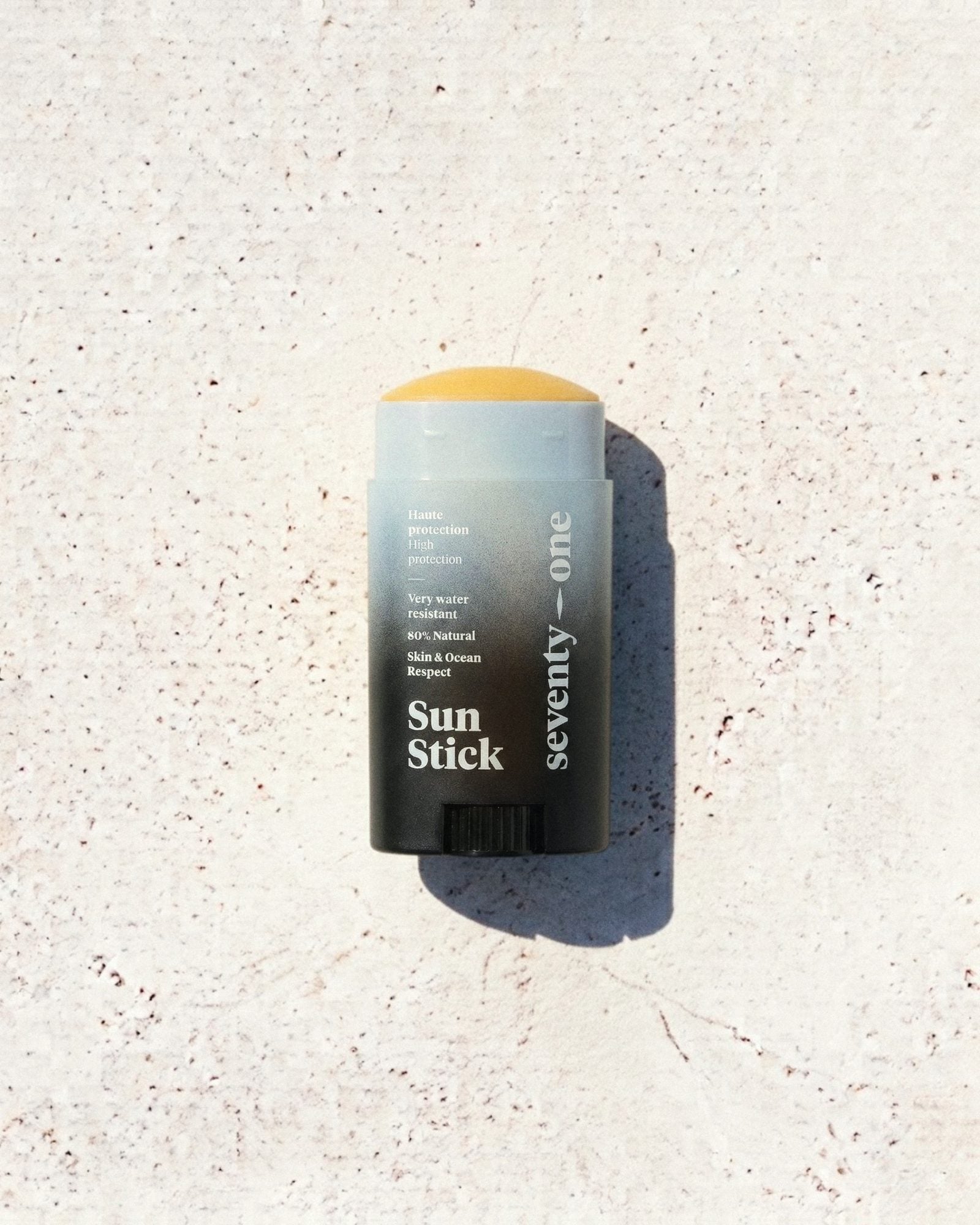 Stick solaire The Invisible SPF 50 SeventyOne Percent, haute protection très résistant à l'eau 15 g, posé sur une pierre blanche au soleil