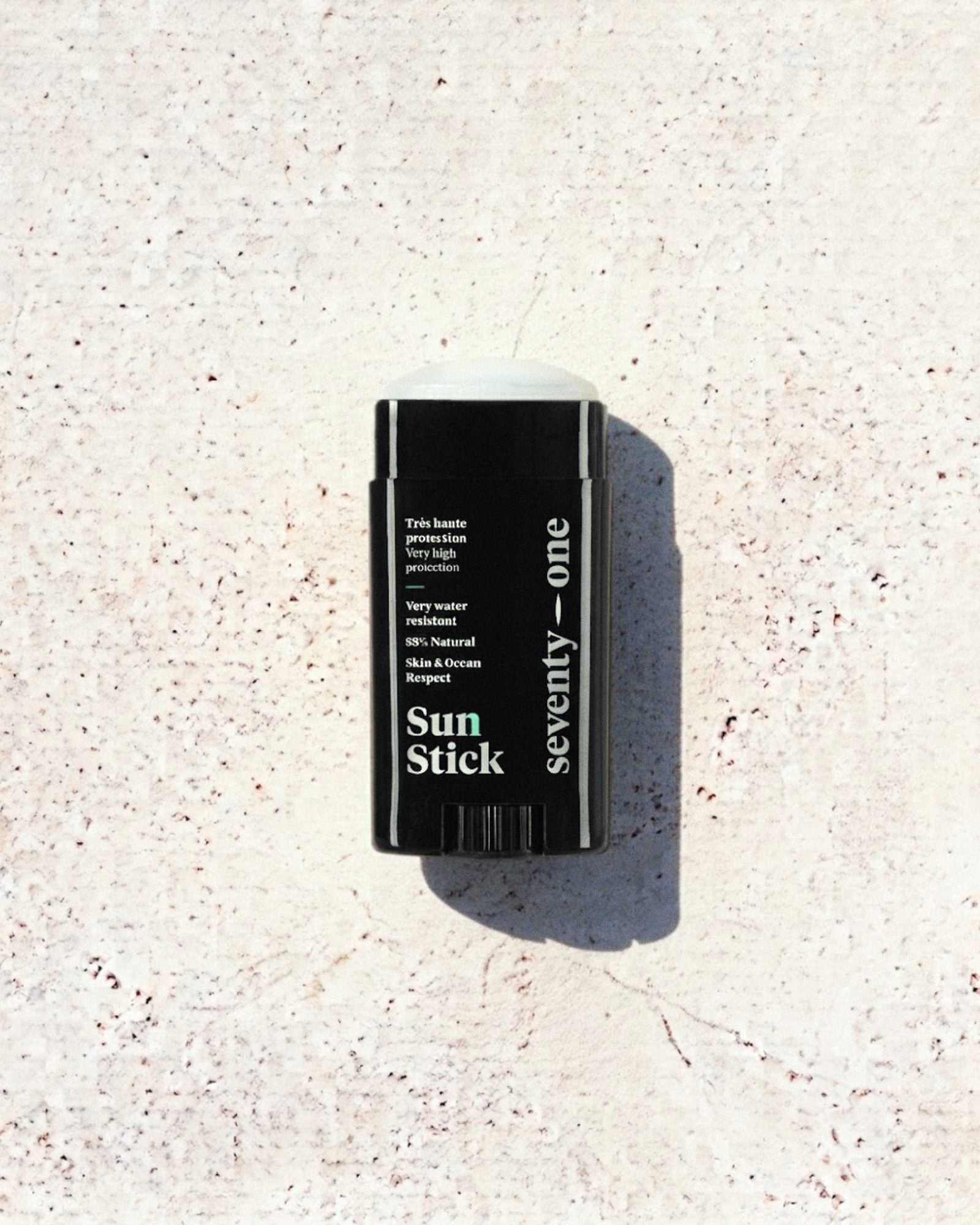 Stick solaire The Original SPF 50+ SeventyOne Percent, très haute protection résistant à l'eau 15 g, posé sur une pierre blanche au soleil